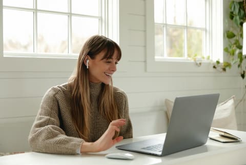 Woman Working at her laptop with ear buds in Woman Working at her laptop with ear buds in
