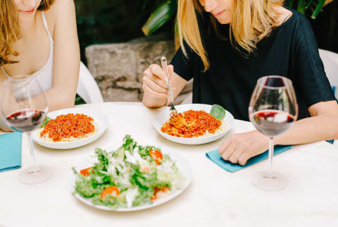 Women Sitting at Restaurant Eating Spaghetti and Drinking Wine Women Sitting at Restaurant Eating Spaghetti and Drinking Wine